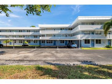 Three-story condo building with parking and a blue exterior with white lattice balconies under a partly cloudy sky at 4720 Locust Ne St # 206, St Petersburg, FL 33703