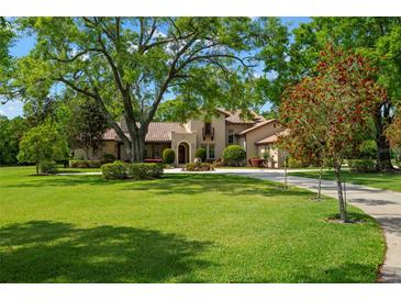 Stunning home featuring mature trees, lush lawn, and a circular driveway, exuding curb appeal at 7775 Still Lakes Dr, Odessa, FL 33556
