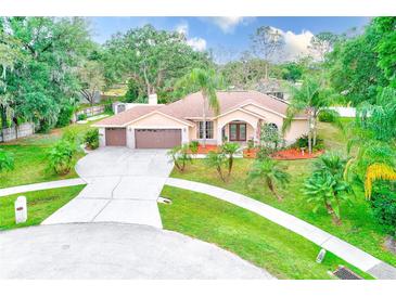 Beautiful single-story home with a three-car garage, well-manicured lawn, and mature landscaping at 12302 Knight Pl, Thonotosassa, FL 33592