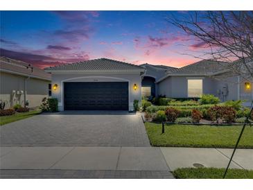 Beautiful single-story home with a well-manicured lawn, landscaped garden beds, and a dark two-car garage at 4734 Avila Lakes Dr, Wimauma, FL 33598
