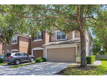 Two story tan home featuring an attached two car garage and mature shade tree at 4920 Pond Ridge Dr, Riverview, FL 33578