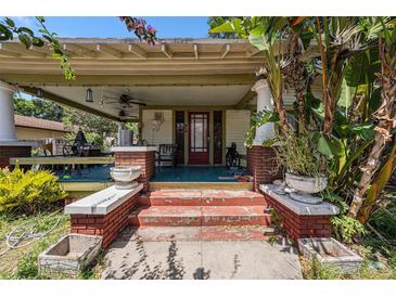 Inviting front porch with brick accents and a covered seating area, framed by mature trees and colorful plantings at 910 E North Bay St, Tampa, FL 33603