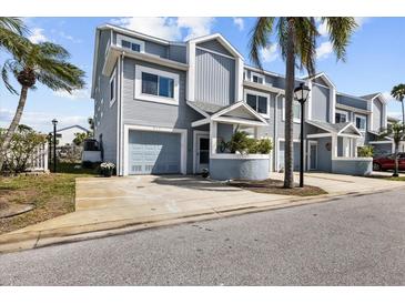 Charming townhouse with light-blue siding, well-manicured landscaping, and a private garage at 911 Harbour House Dr, Indian Rocks Beach, FL 33785