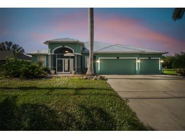 Charming single-story home with a spacious three-car garage, lush lawn, and inviting screened entryway at 1161 Rio De Janeiro Ave, Punta Gorda, FL 33983