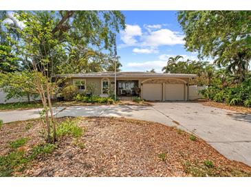 Charming single-story home with mature trees and a spacious driveway leading to a two-car garage at 219 Rialto Ne Way, St Petersburg, FL 33704