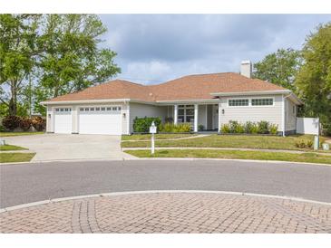 Charming home featuring a three-car garage, well-maintained lawn, and mature trees in a serene neighborhood at 3027 Key Harbor Dr, Safety Harbor, FL 34695