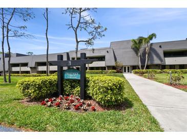 Prestwick condo building featuring well-manicured landscaping, sidewalk, and lush greenery at 36750 Us 19 N # 20211, Palm Harbor, FL 34684