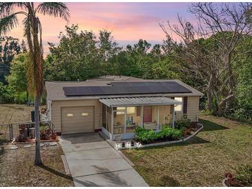 Charming single-Gathering home featuring solar panels, a screened-in porch, and a well-manicured front yard at dusk at 5050 68Th N Way, St Petersburg, FL 33709