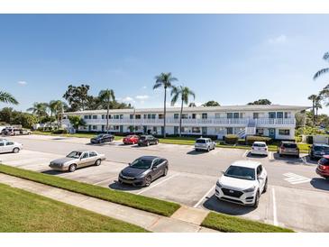 Apartment complex with a large parking lot, tropical landscaping, blue accents, and white exterior at 8555 112Th St # 209, Seminole, FL 33772