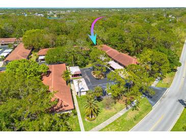 An aerial view of Scottsdale Villas I shows lush landscaping, mature trees and tile roofs at 1201 Montrose Pl, Dunedin, FL 34698