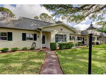 Charming single-story home featuring a well-manicured lawn and lovely landscaping with decorative shutters and walkway at 1466 Normandy Park Dr # 4, Clearwater, FL 33756