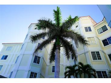 Exterior angle shot of cream and white condominium building with a red tile roof and a palm tree in front of it at 1860 N Fort Harrison Ave # 301, Clearwater, FL 33755