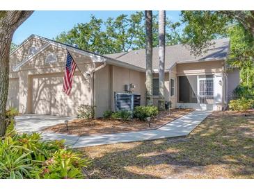 Charming home featuring a two-car garage, manicured landscaping, and an inviting entrance at 5245 Lochmead Ter, Zephyrhills, FL 33541