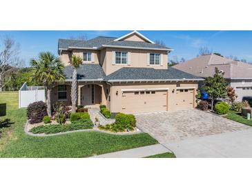 Charming two-story home boasts a manicured lawn, brick driveway, and an attached three-car garage at 8247 Westhaven Dr, Land O Lakes, FL 34638