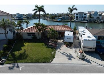 Charming waterfront home featuring a tile roof, lush landscaping, and a spacious driveway for RV parking at 187 175Th Terrace E Dr, Redington Shores, FL 33708