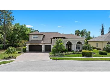 Charming home with lush landscaping, brick driveway, and three-car garage on a serene day at 21654 Draycott Way, Land O Lakes, FL 34637