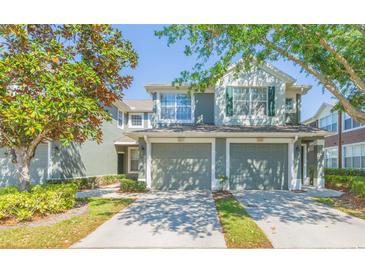Inviting townhome featuring a two-car garage, neutral paint, and mature trees providing shade at 2211 Kings Palace Dr, Riverview, FL 33578