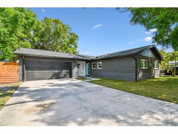 Charming single story home with a well-manicured lawn, dark brick, garage and a concrete driveway at 5907 Tampa Shores Blvd, Tampa, FL 33615