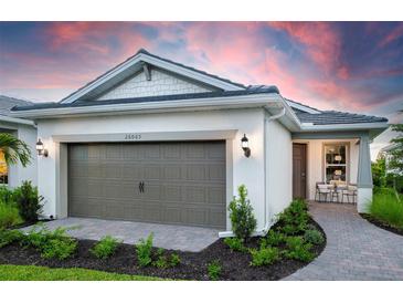 Charming home featuring a two-car garage, well-manicured landscaping, and a cozy front porch at 6132 Wire Grass Ct, Nokomis, FL 34275