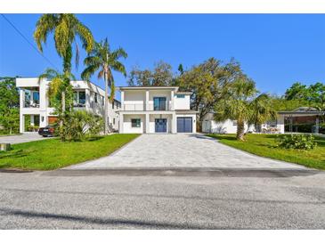 Stunning two-story home with a blue door, attached garage, and a spacious paver driveway at 1045 Jesse Ave, Safety Harbor, FL 34695