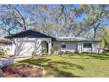 Charming single-story home with a well-manicured lawn and an attached garage, all shaded by mature trees at 2004 Nobleton Ave, Spring Hill, FL 34608