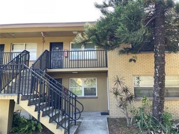 Two-story apartment building featuring exterior stairs and a mature tree in a landscaped yard at 2500 Harn Blvd # B11, Clearwater, FL 33764