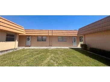 Charming exterior of a single-story home featuring a well-manicured lawn and peach-colored facade at 1801 Bedford Ln # 46, Sun City Center, FL 33573