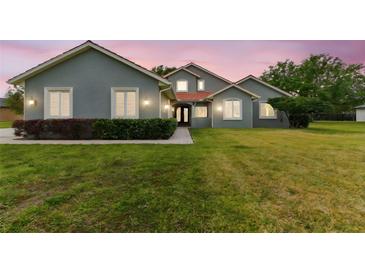 Charming home featuring a well-manicured lawn, lush shrubbery and a red tile roof at 18502 Keystone Manor Rd, Odessa, FL 33556
