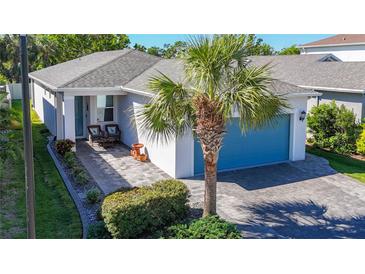 Charming single-story home with a blue garage door, paver driveway and walkway, and lush tropical landscaping at 5415 Los Robles Ct, Palmetto, FL 34221