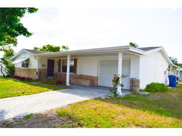 Charming single-story home with white siding, stone accents, and a well-manicured lawn at 7435 Hollyridge Dr, New Port Richey, FL 34653