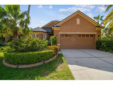 Charming home featuring a well-manicured lawn, lush landscaping, and an attached two-car garage at 10418 Applecross Ln, Tampa, FL 33626