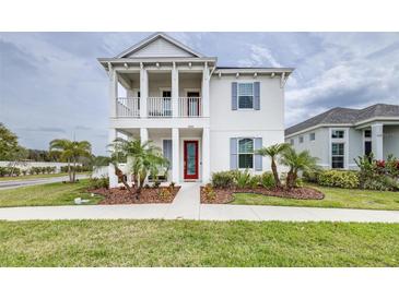 Inviting two-story home featuring a charming front porch and beautifully landscaped front yard with palm trees at 3706 Front Park Dr, Wesley Chapel, FL 33543