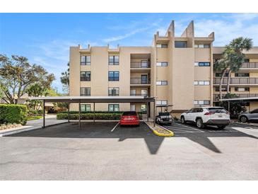 Condominium building featuring a covered parking area and well-maintained landscaping at 2614 Cove Cay Dr # 301, Clearwater, FL 33760