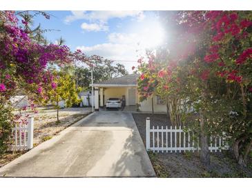Charming home featuring a covered carport, a cozy front yard with colorful flowers and a white picket fence at 2819 N 75 St, Tampa, FL 33619
