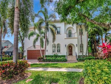 Elegant two-story home with a lush lawn, mature trees, and a beautiful Mediterranean-style facade at 511 Erie Ave, Tampa, FL 33606