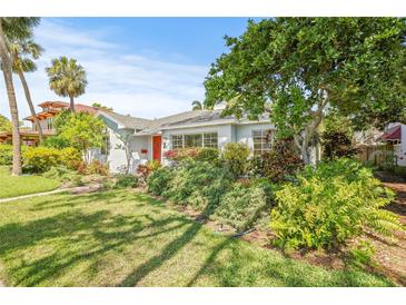 Charming single-story home featuring lush landscaping, a manicured lawn, and a vibrant red front door at 615 14Th Ne Ave, St Petersburg, FL 33701