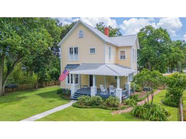 Charming two-story home with a welcoming front porch, complemented by a lush green lawn and mature trees at 14006 5Th St, Dade City, FL 33525