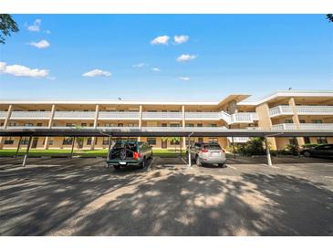 Exterior of a condominium building with covered parking on a sunny day, ample parking spaces, and well-maintained landscaping at 5080 Locust Ne St # 321, St Petersburg, FL 33703