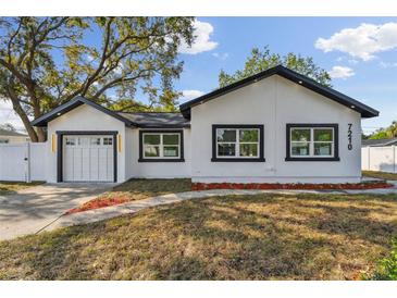 Beautiful exterior of white home with black accents, large windows and well-manicured lawn at 7210 8Th N Ave, St Petersburg, FL 33710