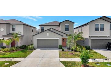 Charming two-story home with a well-manicured lawn, gray exterior, and attached two-car garage at 7331 Canterbury Bells Ct, Tampa, FL 33619