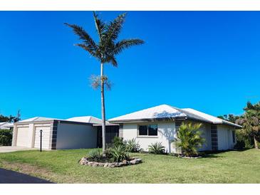 Charming single-story home featuring a well-manicured lawn and a large palm tree against a clear blue sky at 208 Villa Dr # 208, Osprey, FL 34229