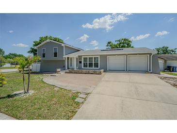 Charming home featuring a two-car garage, brick accents, and a well-maintained front yard under a bright sky at 7015 Cobblewood Ct, Tampa, FL 33615