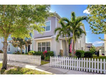 Charming two-story home featuring a picket fence, lush landscaping, and a welcoming entrance with beautiful palm trees at 11309 Grand Park Ave, Riverview, FL 33578