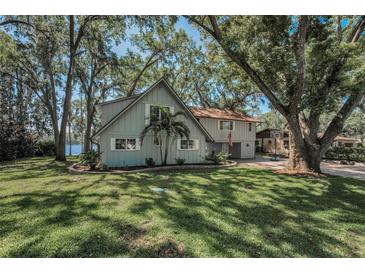 Charming two-story lakefront home with beautiful landscaping, mature trees, and large grassy yard at 16019 Chastain Rd, Odessa, FL 33556