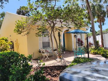 Charming yellow home with a brick-paved patio, seating, and a blue umbrella at 2512 W Texas Ave # C, Tampa, FL 33629