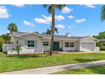 Charming white brick home with a well-manicured lawn, palm trees and a light gray roof at 3945 Versailles Dr, Tampa, FL 33634