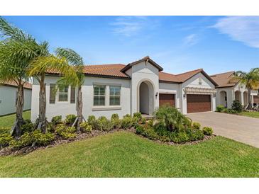 Beautiful single-story home with a well-manicured lawn, lush landscaping, and a tile roof at 5313 Windy Grove Dr, Wimauma, FL 33598