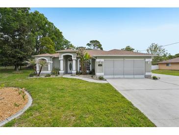 Charming single-story home featuring a well-manicured lawn and an inviting front entrance with beautiful landscaping at 2016 Alameda Dr, Spring Hill, FL 34609