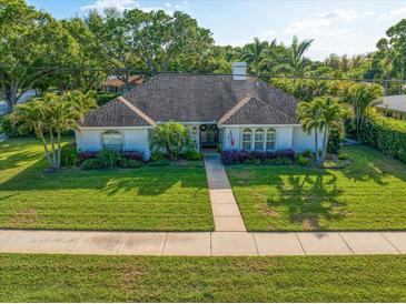 Charming single-story home with a lush green lawn, mature trees, and beautifully landscaped flowerbeds at 307 Oleander Rd, Belleair, FL 33756