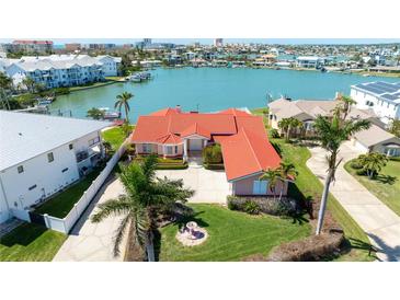 Stunning waterfront home with a red tile roof, lush landscaping, and panoramic water views at 320 Bath Club Blvd S, North Redington Beach, FL 33708
